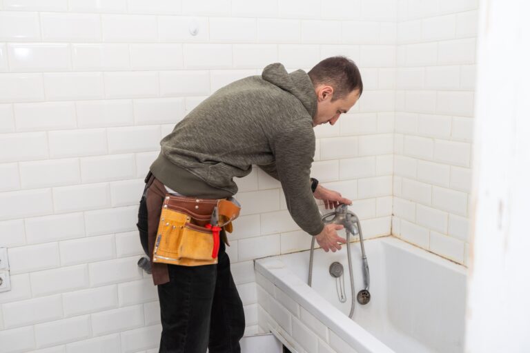 A male plumber with wrench repairs the faucet in the bathroom. replacement and maintenance of