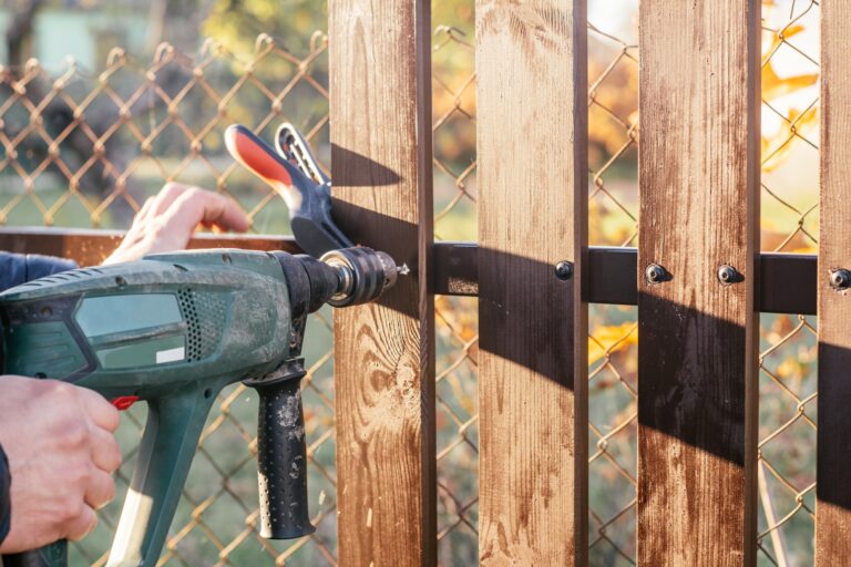 Hand of carpenter holding electric drill for making hole into wooden plank to metal construction