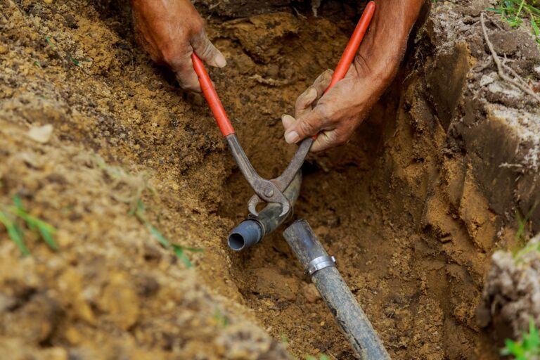 Man Applying Solvent Primer and Cement to PVC Pipes as Part of Installation of Underground automatic